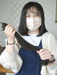 ヘアドネーションした黒髪を手に笑顔の佐々木さん