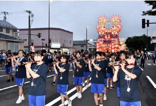 威勢のいい囃子を奏でながら街なかを練り歩く能代一中の生徒）