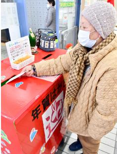 年賀状の引き受けが全国一斉に始まった15日、能代山本でも投函する人が見られた（能代郵便局で）