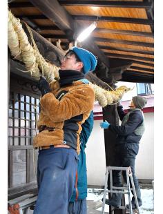 新しいしめ縄を中川原稲荷神社の社殿に飾り付けたメンバー（能代市中川原で）