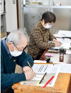 年賀状の宛て名を丁寧に書き進める筆耕班のメンバー（能代市青葉町で）