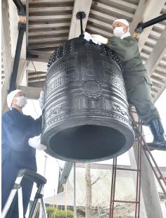 大みそかを前に、梵鐘を丁寧に磨き上げる武田住職ら（八峰町八森の松源院で）