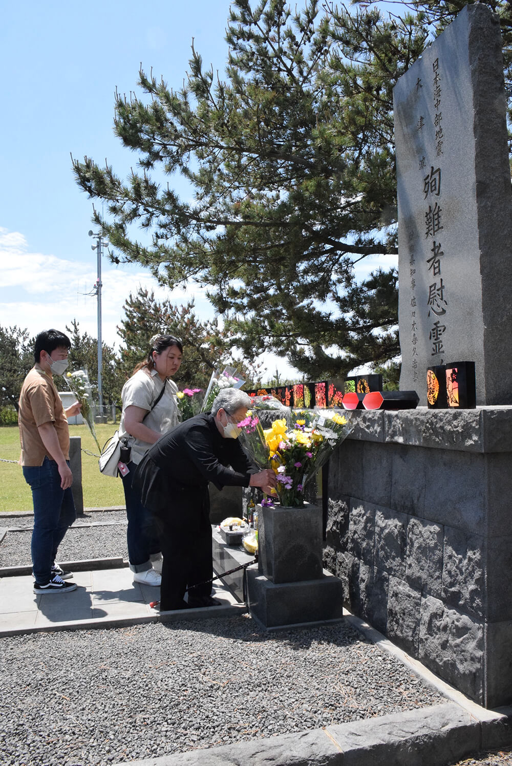 慰霊碑に花を手向け、津波で命を落とした人たちの冥福を祈る遺族ら