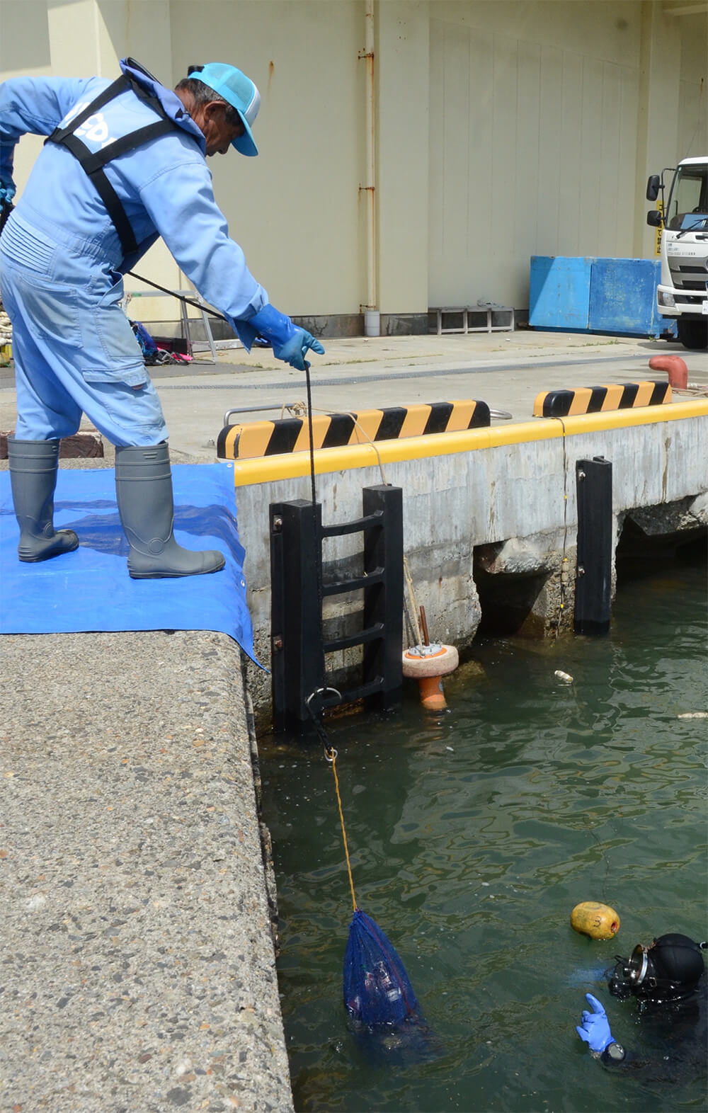 潜水士が海中から拾い集めたごみを陸上に引き上げ（八峰町の八森漁港で）