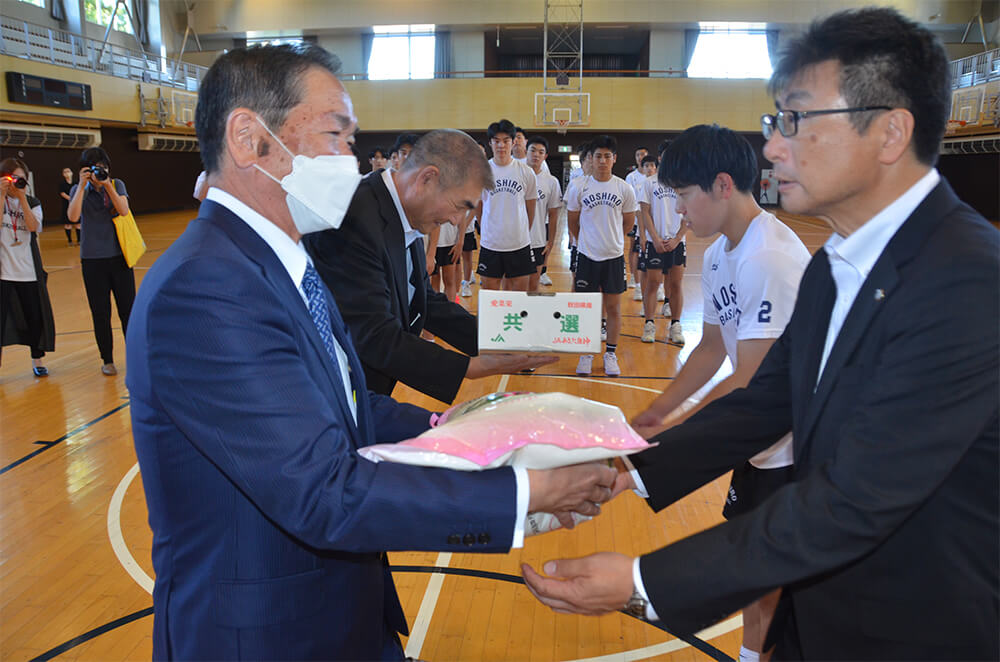 地元農家が丹精こめて生産したあきたこまちと白神ねぎを贈呈（能代科技高体育館で）