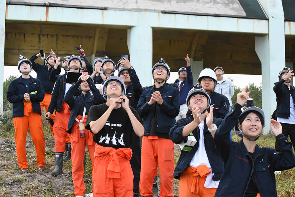 打ち上げの成功を喜ぶ学生たち（能代市の落合浜で）