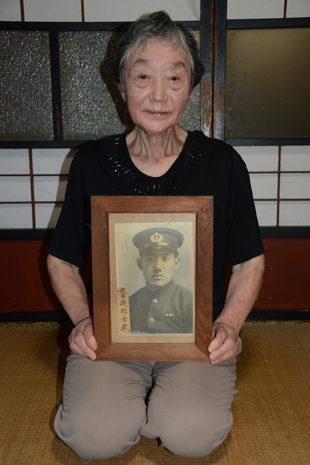 戦時中の昭和17年に建てられた能代市落合の実家で父の遺影を抱く渡部さん