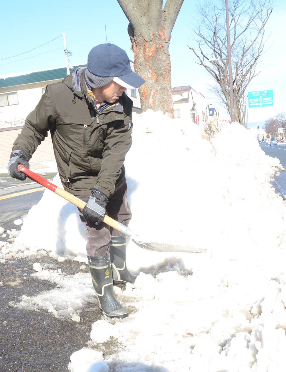 気温が上昇し、解けだした雪の片付けに追われる市民（能代市西通町で）